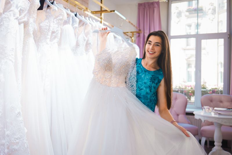 A beautiful bride holding a wedding dress in a wedding boutique